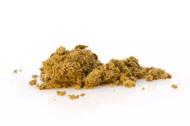 Hachís de cbd tipo polen, desmenuzado sobre superficie blanca reflectante