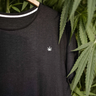 camiseta negra sobre fondo de plantas de cáñamo